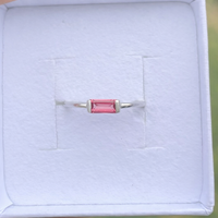 Silver ring with a Padparadascha gemstone on a white cushion