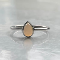 Silver ring with a grey teardrop-shaped stone on a light gray background