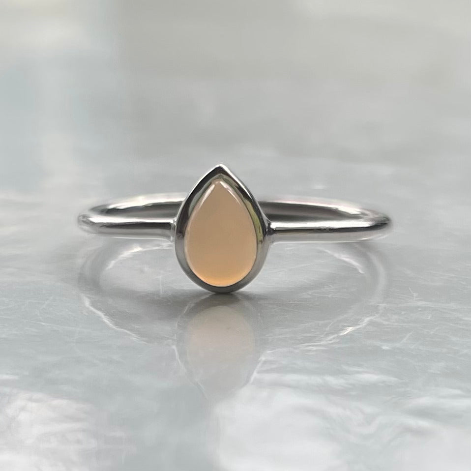 Silver ring with a grey teardrop-shaped stone on a light gray background