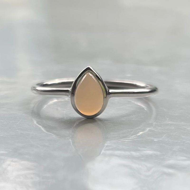 Silver ring with a grey teardrop-shaped stone on a light gray background