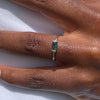 Silver ring with a moss agate gemstone on a person's finger against a white background