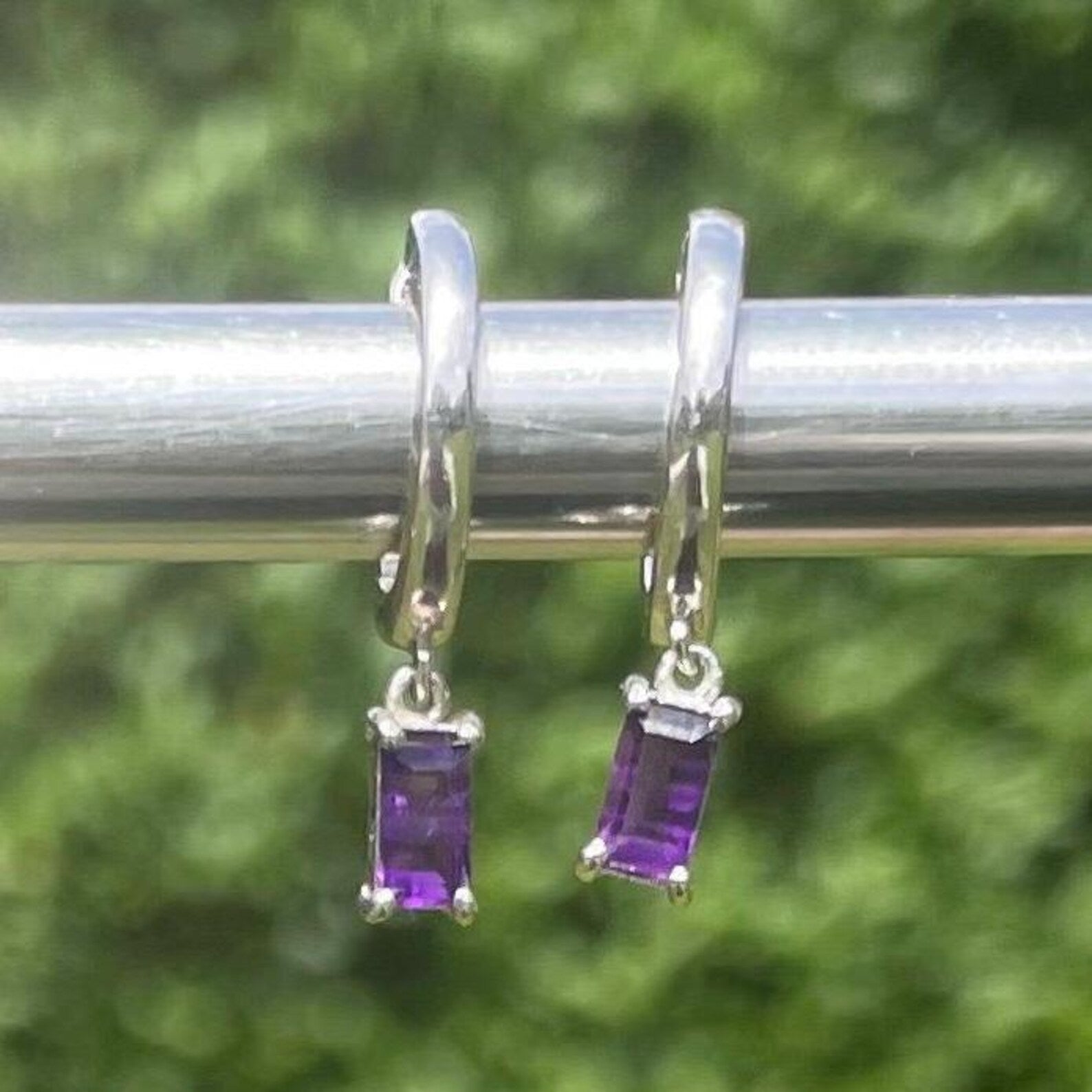 Silver earrings with purple Amethyst gemstones on a green background