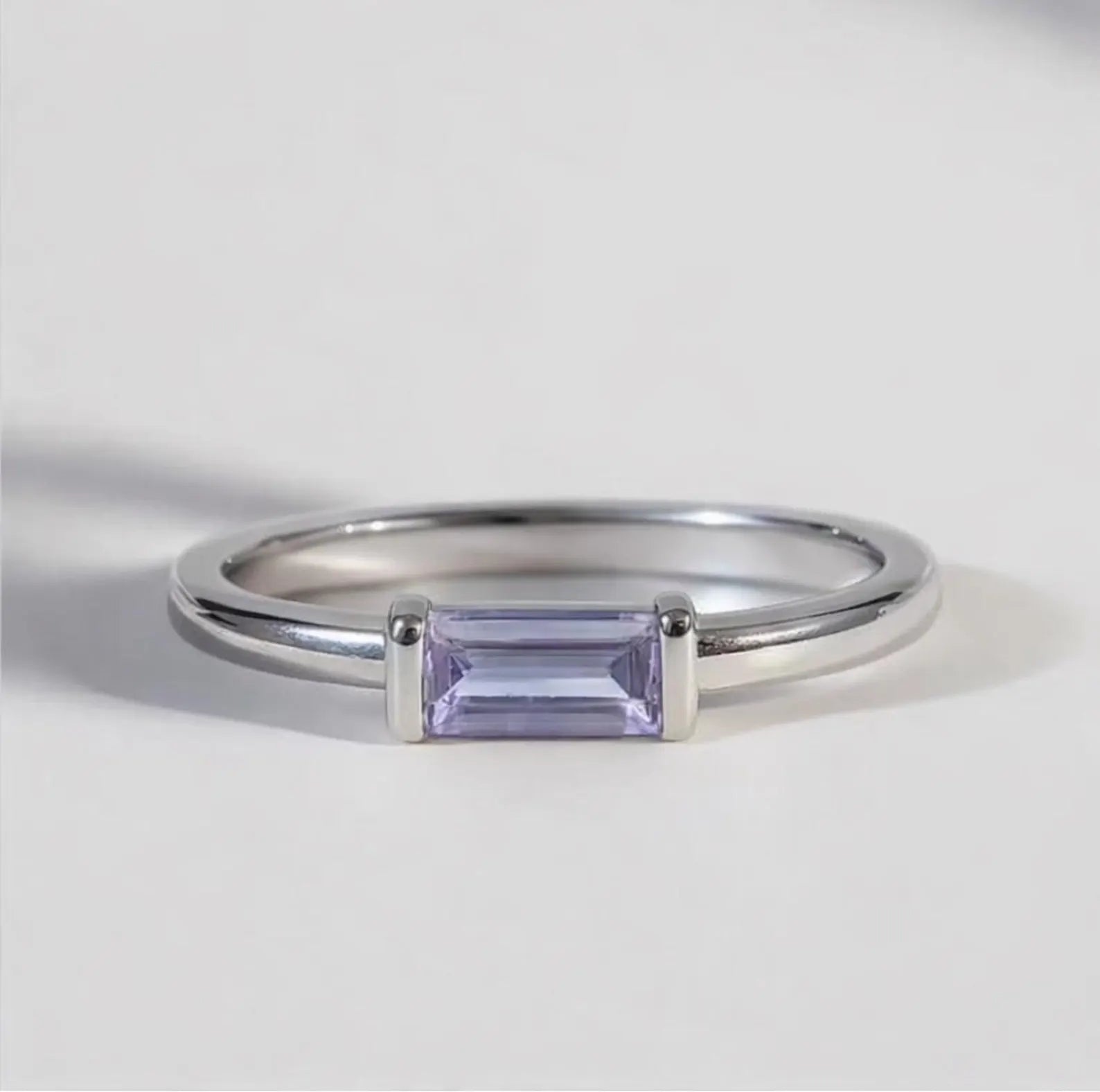 Silver ring with a rectangular Alexandrite gemstone on a light gray background