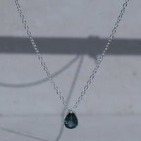 Necklace with a teardrop-shaped blue gemstone pendant on a light gray background