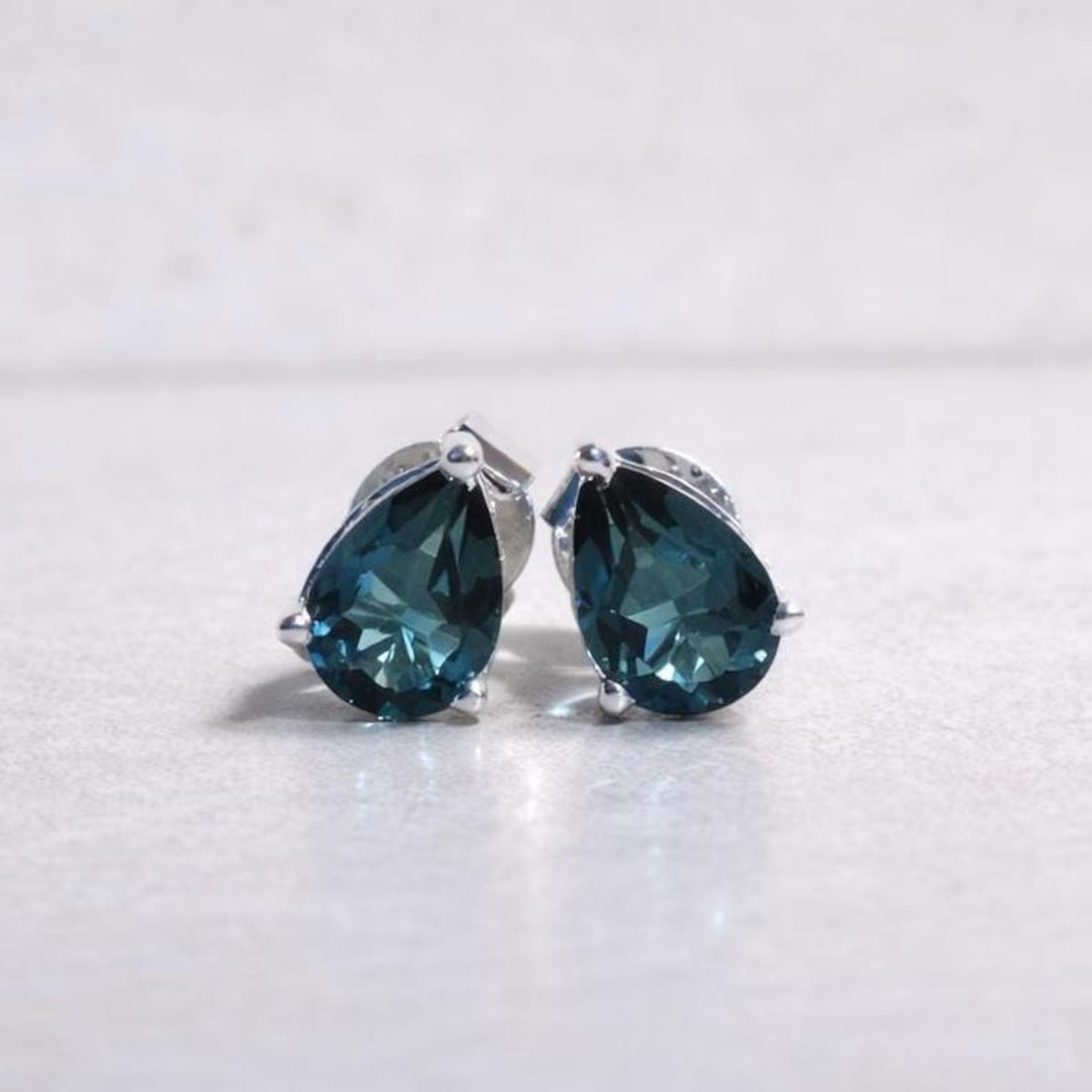 Pair of London blue topaz blue teardrop earrings on a white background