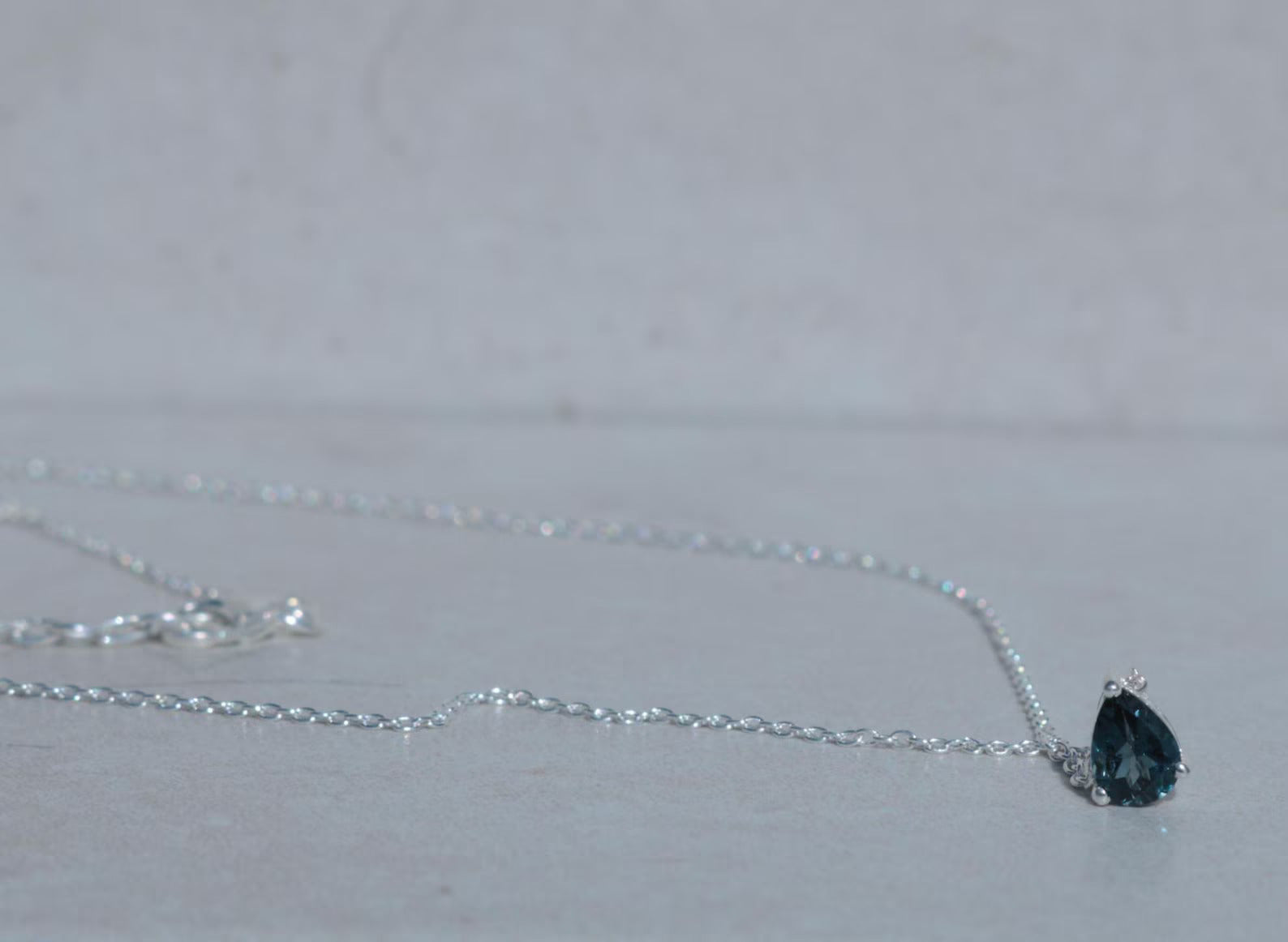 Necklace with a black teardrop-shaped pendant on a light gray background