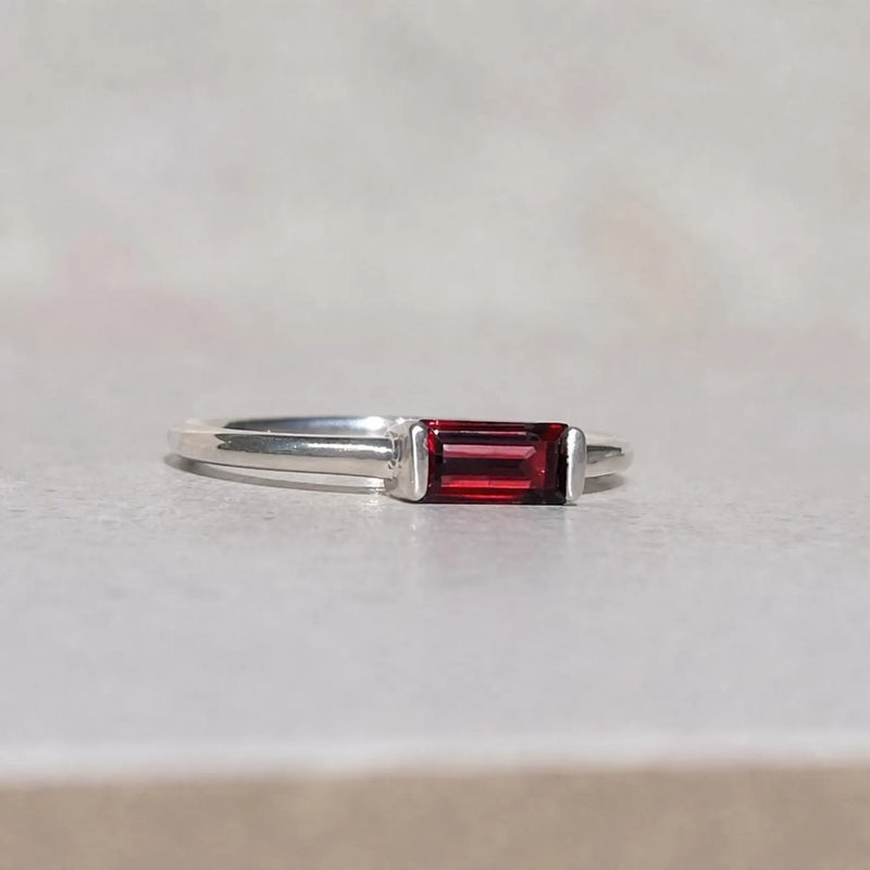 Silver ring with a red garnet gemstone on a light gray background