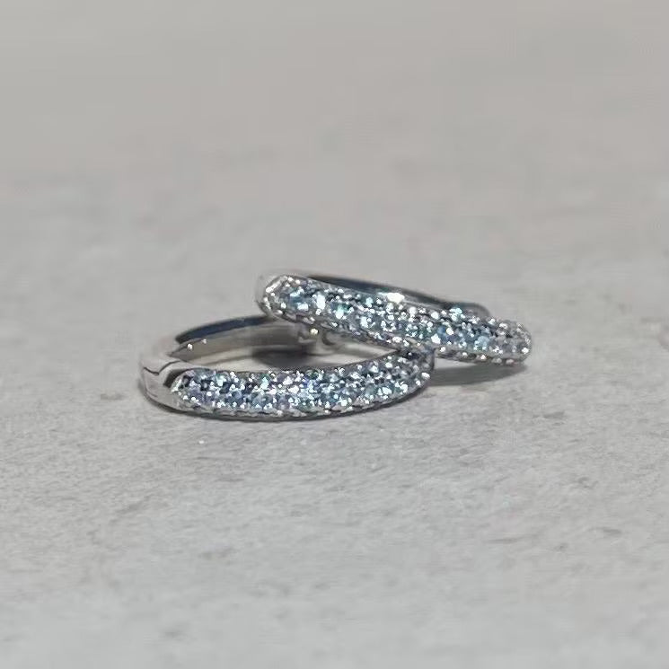 Pair of silver aquamarine hoop earrings with clear gemstones on a light gray background
