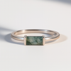 Silver ring with a rectangular moss agate gemstone on a light background