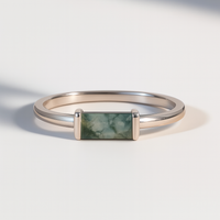 Silver ring with a rectangular moss agate gemstone on a light background