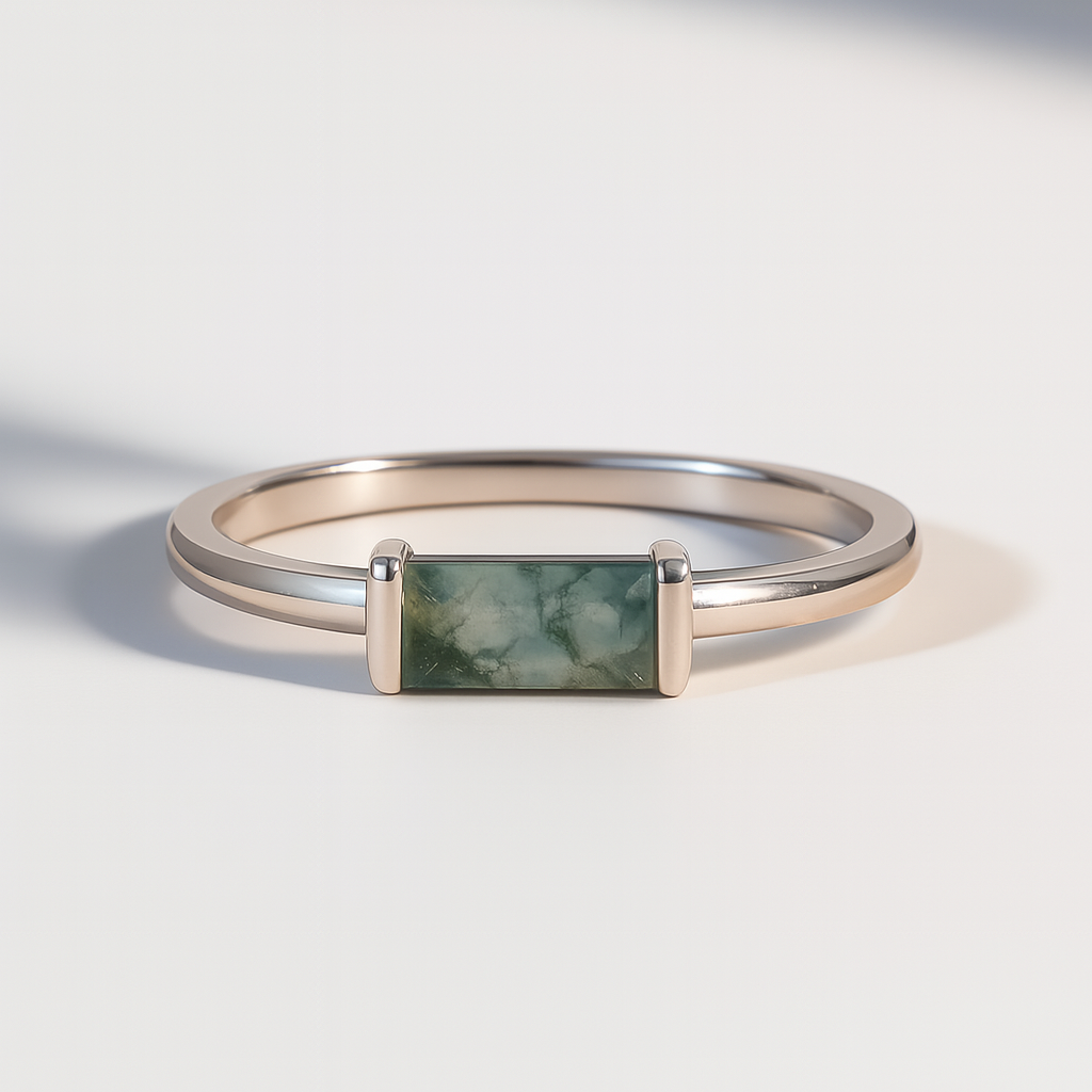 Silver ring with a rectangular moss agate gemstone on a light background